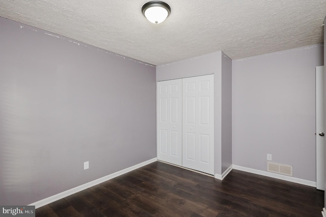 unfurnished bedroom with dark hardwood / wood-style flooring, a closet, and a textured ceiling