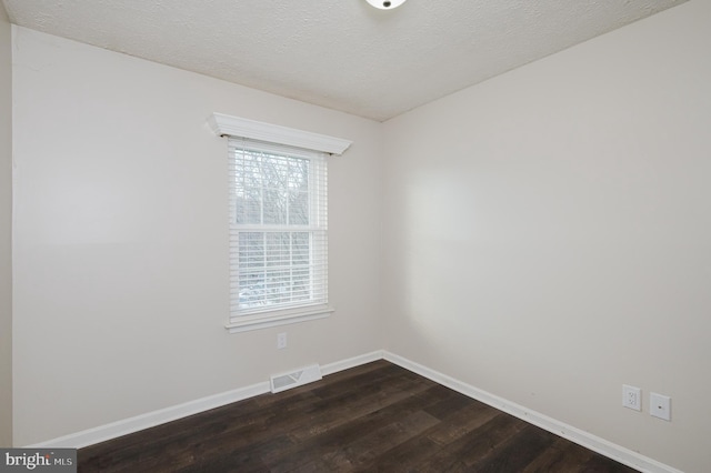 spare room featuring dark wood-type flooring and a textured ceiling