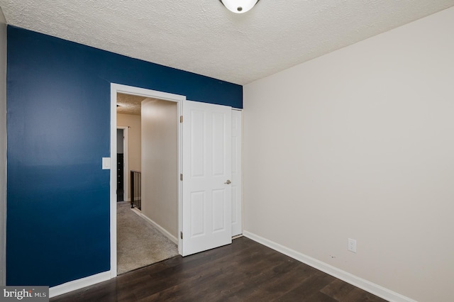 empty room featuring dark wood-type flooring and a textured ceiling