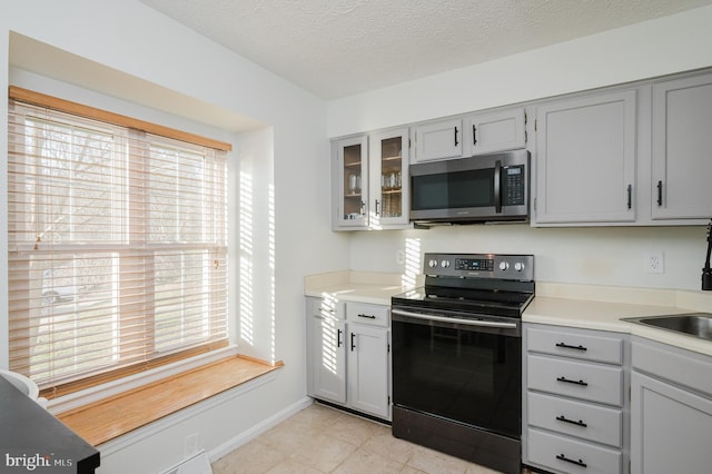 kitchen with gray cabinets, electric range oven, and a textured ceiling