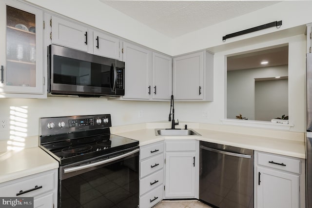 kitchen with stainless steel appliances, sink, white cabinets, and a textured ceiling