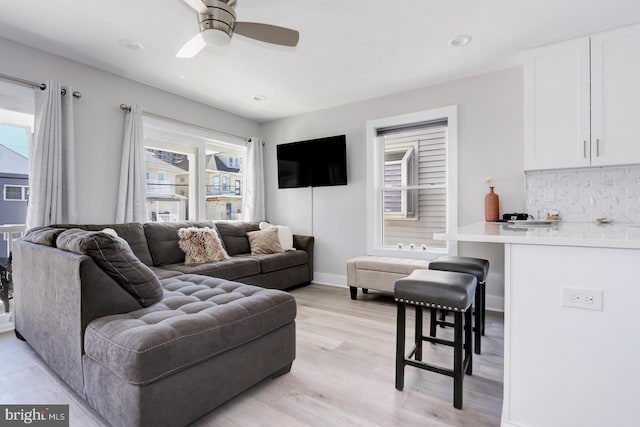 living room with ceiling fan, plenty of natural light, and light hardwood / wood-style floors