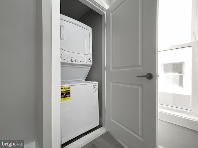 washroom featuring hardwood / wood-style floors and stacked washer / drying machine