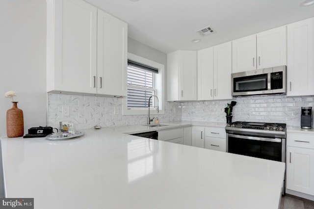 kitchen with decorative backsplash, stainless steel appliances, sink, white cabinets, and light hardwood / wood-style floors