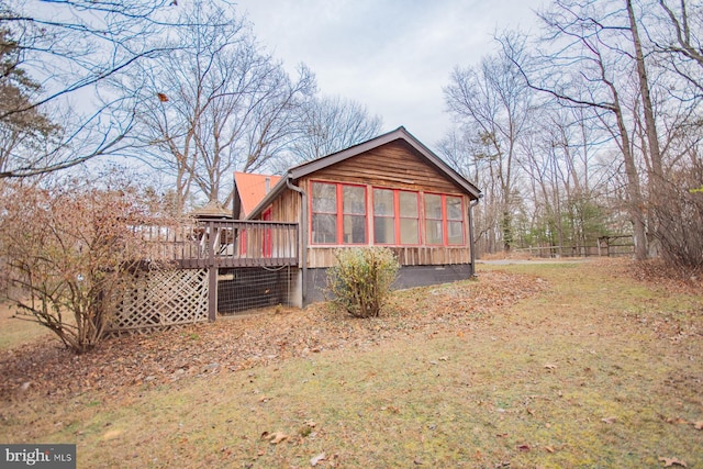 view of side of property with a sunroom, a deck, and a yard