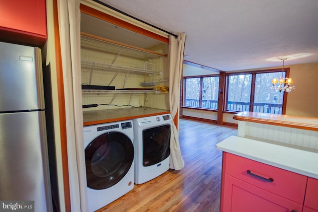 laundry area featuring light hardwood / wood-style floors, an inviting chandelier, and washer and clothes dryer