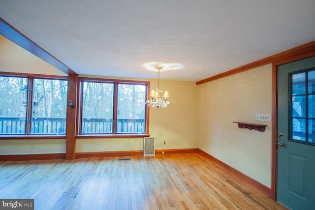 interior space with a wealth of natural light, hardwood / wood-style floors, crown molding, and a notable chandelier