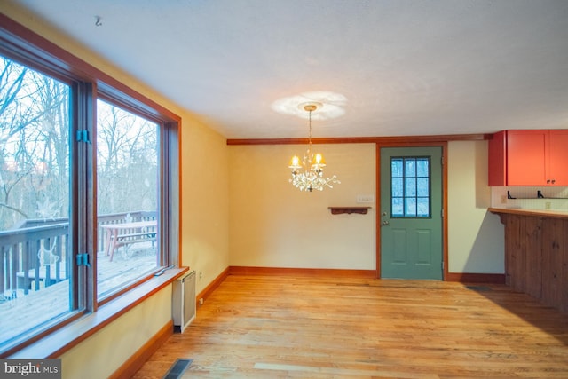 unfurnished dining area featuring a notable chandelier, plenty of natural light, and light wood-type flooring