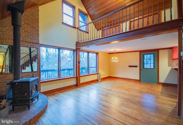 living room with a wood stove, a chandelier, light hardwood / wood-style flooring, and a healthy amount of sunlight