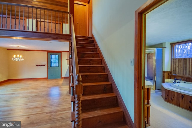 stairway with hardwood / wood-style floors and an inviting chandelier