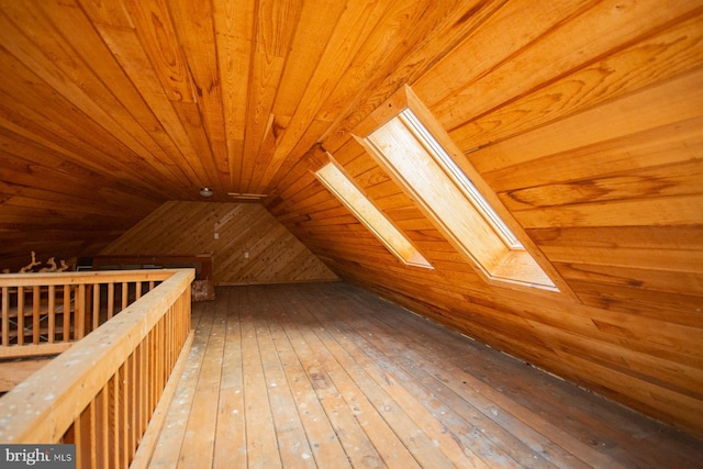 additional living space with hardwood / wood-style floors, wood ceiling, wooden walls, and vaulted ceiling with skylight