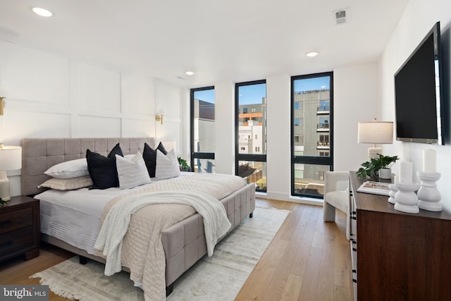 bedroom with expansive windows and light hardwood / wood-style floors