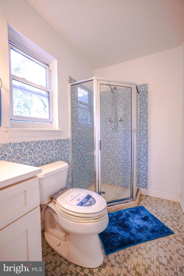 bathroom with tile patterned floors, vanity, toilet, and a shower with door