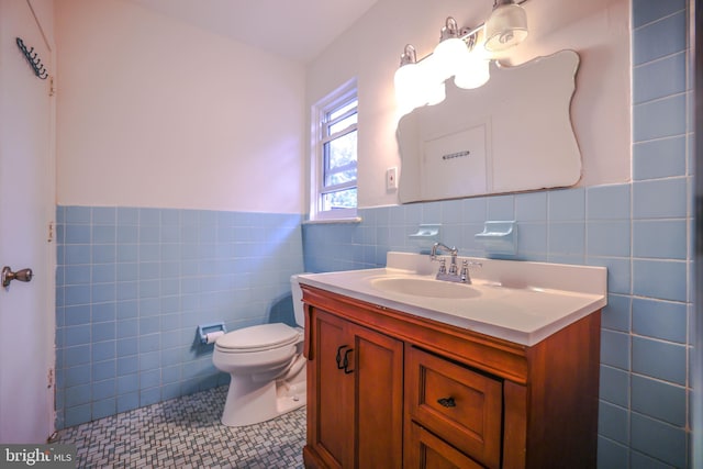 bathroom with tile patterned flooring, vanity, toilet, and tile walls