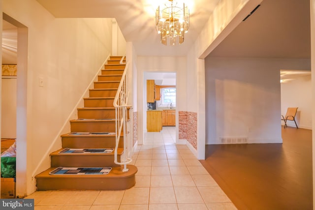 staircase with tile patterned floors and a chandelier