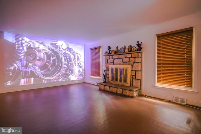 unfurnished living room with hardwood / wood-style floors and a stone fireplace