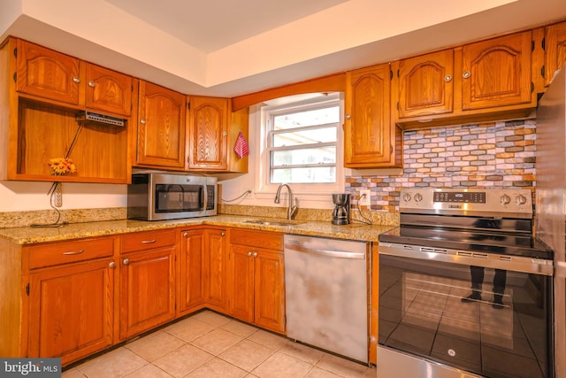 kitchen with light stone counters, sink, light tile patterned flooring, and stainless steel appliances