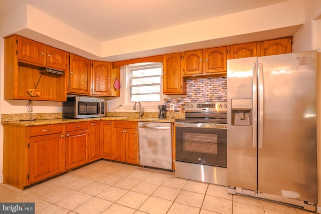 kitchen featuring backsplash, light stone counters, stainless steel appliances, sink, and light tile patterned flooring