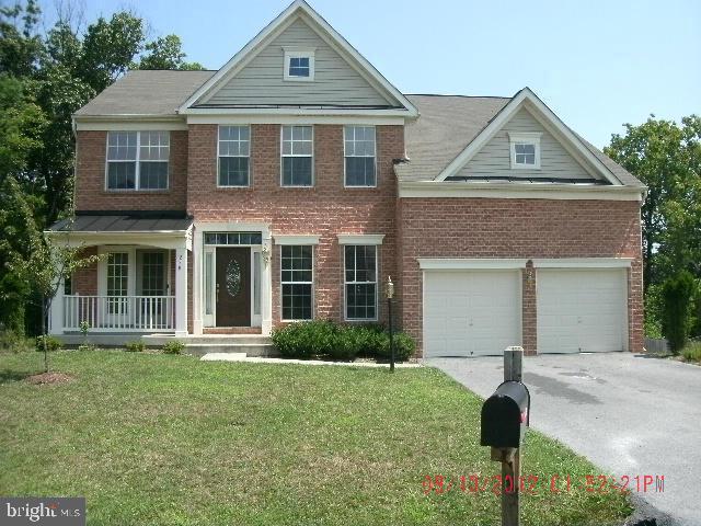 view of front of home featuring a porch, a garage, and a front lawn