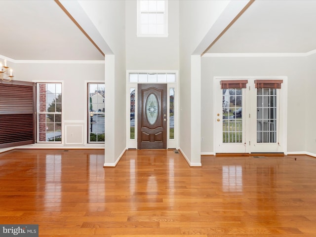 foyer with light wood-type flooring, ornamental molding, and a notable chandelier