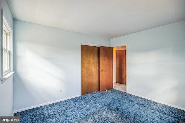 unfurnished bedroom featuring a closet and light colored carpet