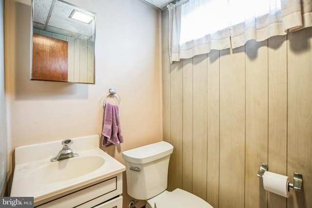 bathroom featuring vanity, toilet, and a drop ceiling