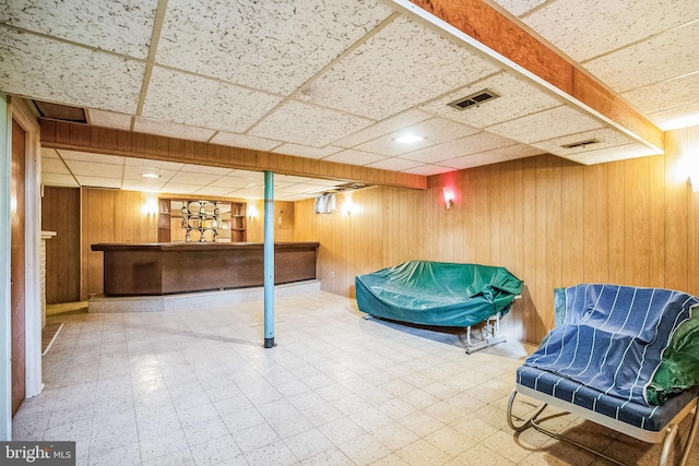 basement with a paneled ceiling and wooden walls