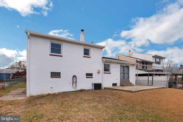 rear view of property featuring a yard, a patio, and central air condition unit