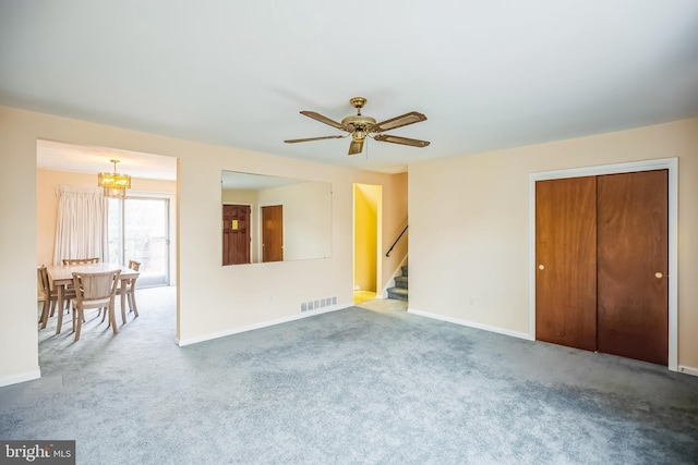 unfurnished living room with carpet flooring and ceiling fan with notable chandelier