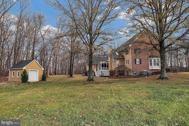 view of yard with a garage, an outbuilding, and central AC