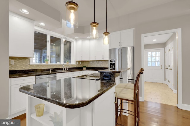 kitchen with white cabinetry, a center island, wood-type flooring, and appliances with stainless steel finishes