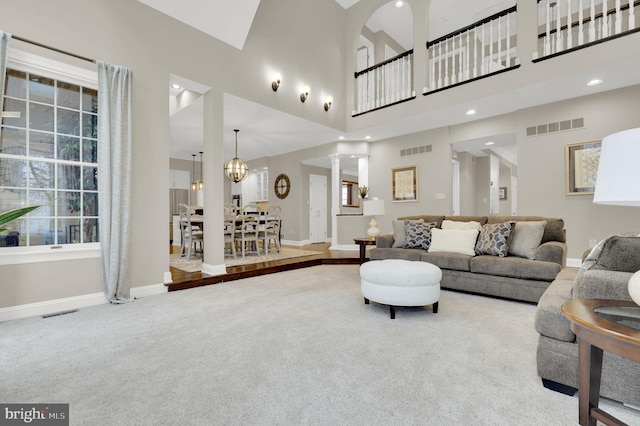 living room with a high ceiling, carpet floors, ornate columns, and plenty of natural light