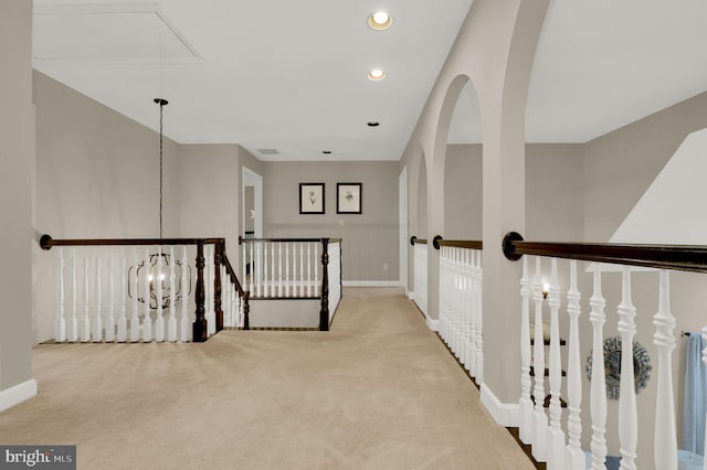 corridor with light carpet and a chandelier