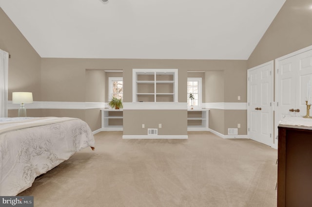 carpeted bedroom with lofted ceiling and two closets