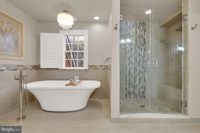 bathroom with tile patterned flooring, shower with separate bathtub, tile walls, and a notable chandelier