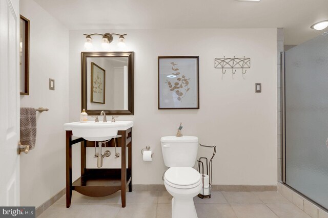 bathroom with tile patterned floors, sink, a shower with shower door, and toilet