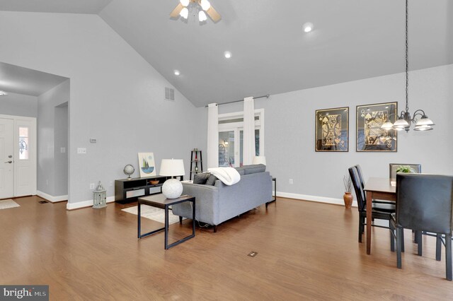 living room featuring hardwood / wood-style floors, ceiling fan with notable chandelier, and high vaulted ceiling