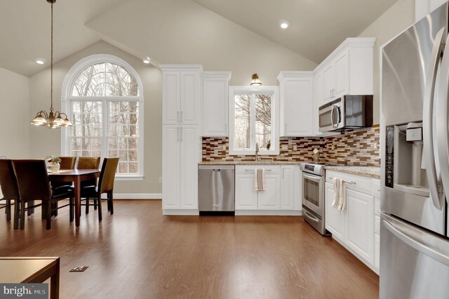 kitchen with hardwood / wood-style flooring, white cabinets, decorative light fixtures, and appliances with stainless steel finishes