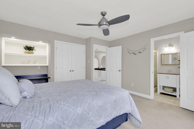 carpeted bedroom featuring ceiling fan, a closet, ensuite bathroom, and sink