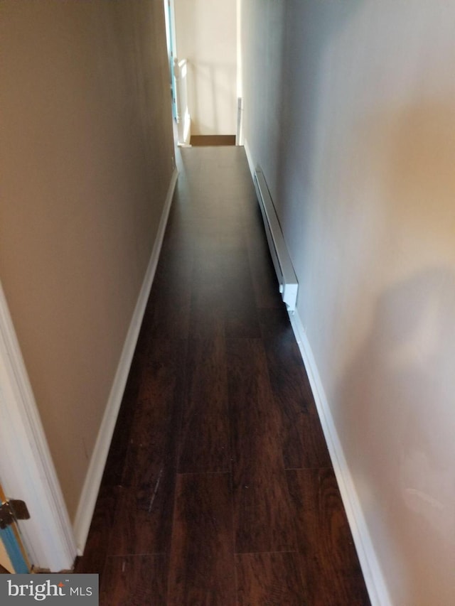 hall with baseboard heating and dark hardwood / wood-style floors