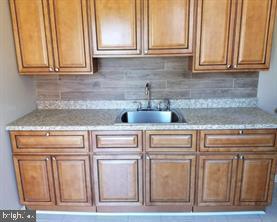 kitchen featuring backsplash, light stone counters, and sink