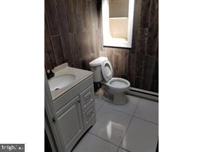 bathroom with vanity, wood walls, tile patterned floors, toilet, and a baseboard radiator