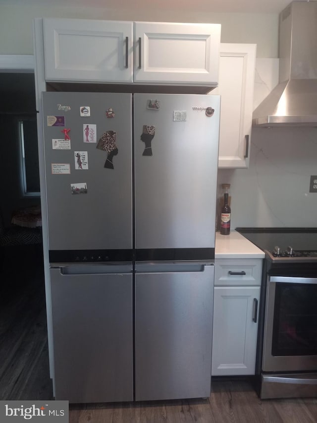 kitchen with white cabinetry, wall chimney exhaust hood, dark hardwood / wood-style floors, and appliances with stainless steel finishes