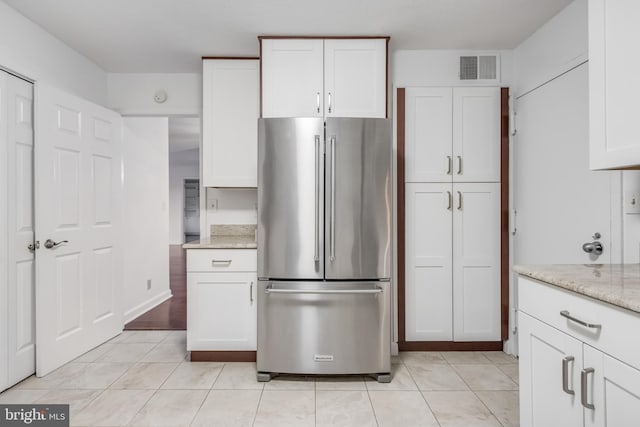 kitchen featuring light stone counters, white cabinetry, and high end refrigerator