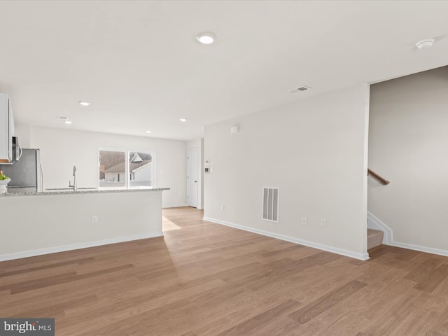 unfurnished living room with light wood-type flooring and sink