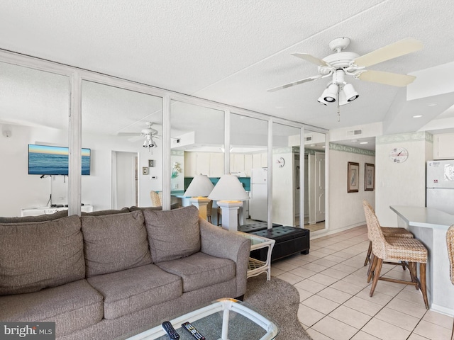 tiled living room featuring ceiling fan and a textured ceiling