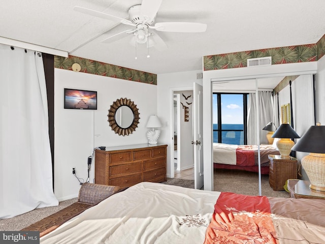 bedroom featuring carpet floors, ceiling fan, and a water view