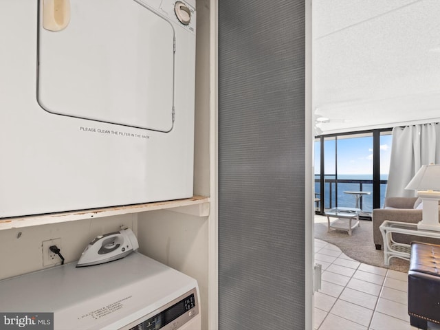 laundry room with stacked washer and dryer, a water view, and light tile patterned floors