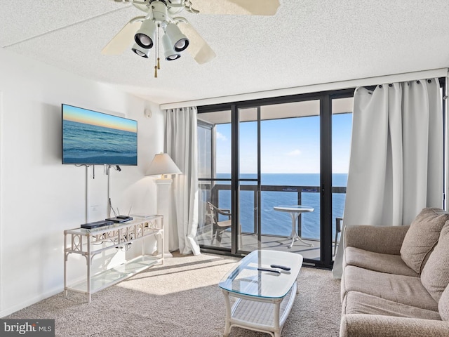 living room with carpet, ceiling fan, floor to ceiling windows, and a textured ceiling