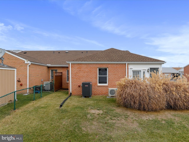 back of property with a lawn, ac unit, and central AC unit